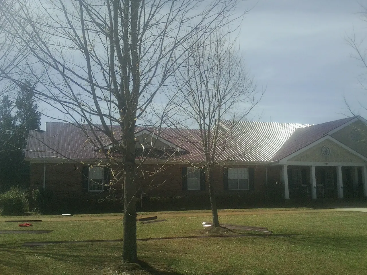 Red metal roof on a brick building seen from the front lawn in Wyoming